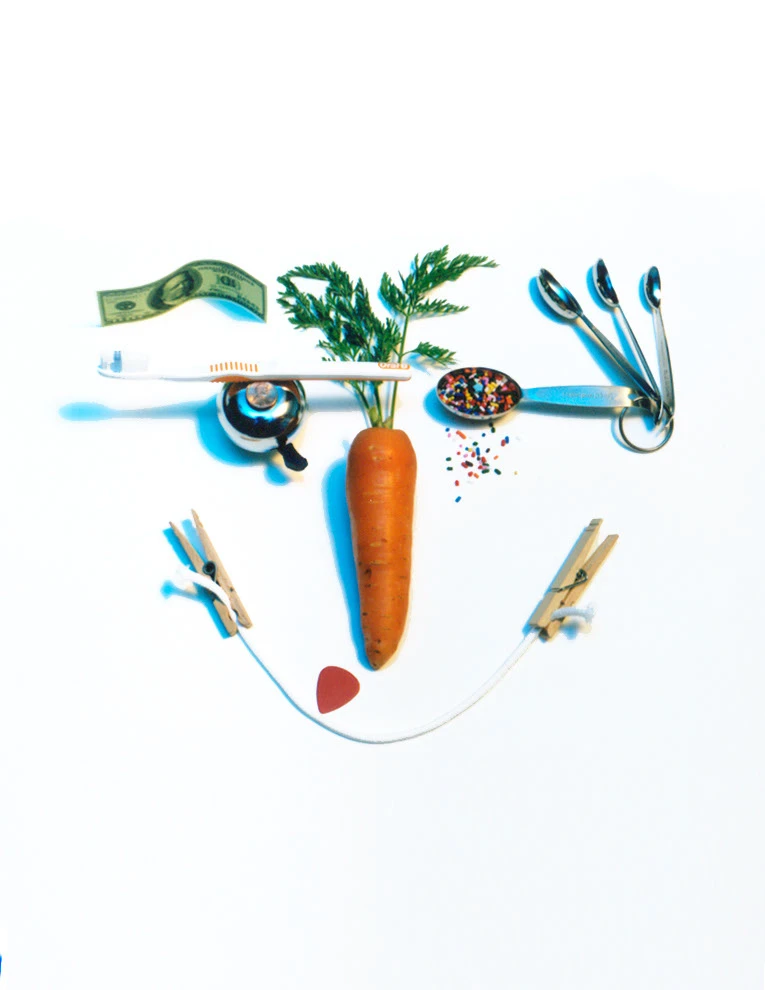 A face assembled from a carrot, toothbrush, kitchen tools, and small objects