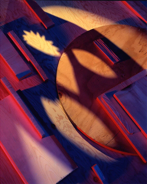 Geometric wooden forms crossed by saturated red and blue light