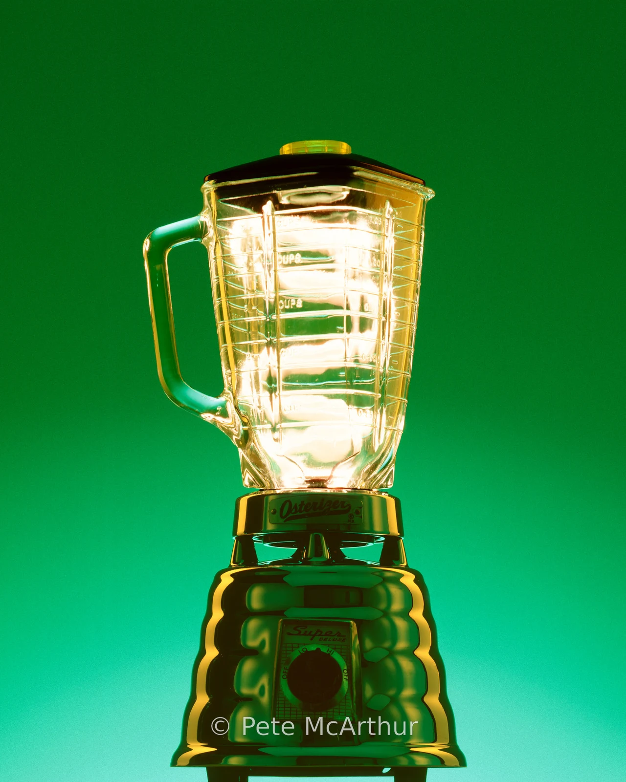 Bright light streaks glow inside the glass pitcher of a reflective blender.