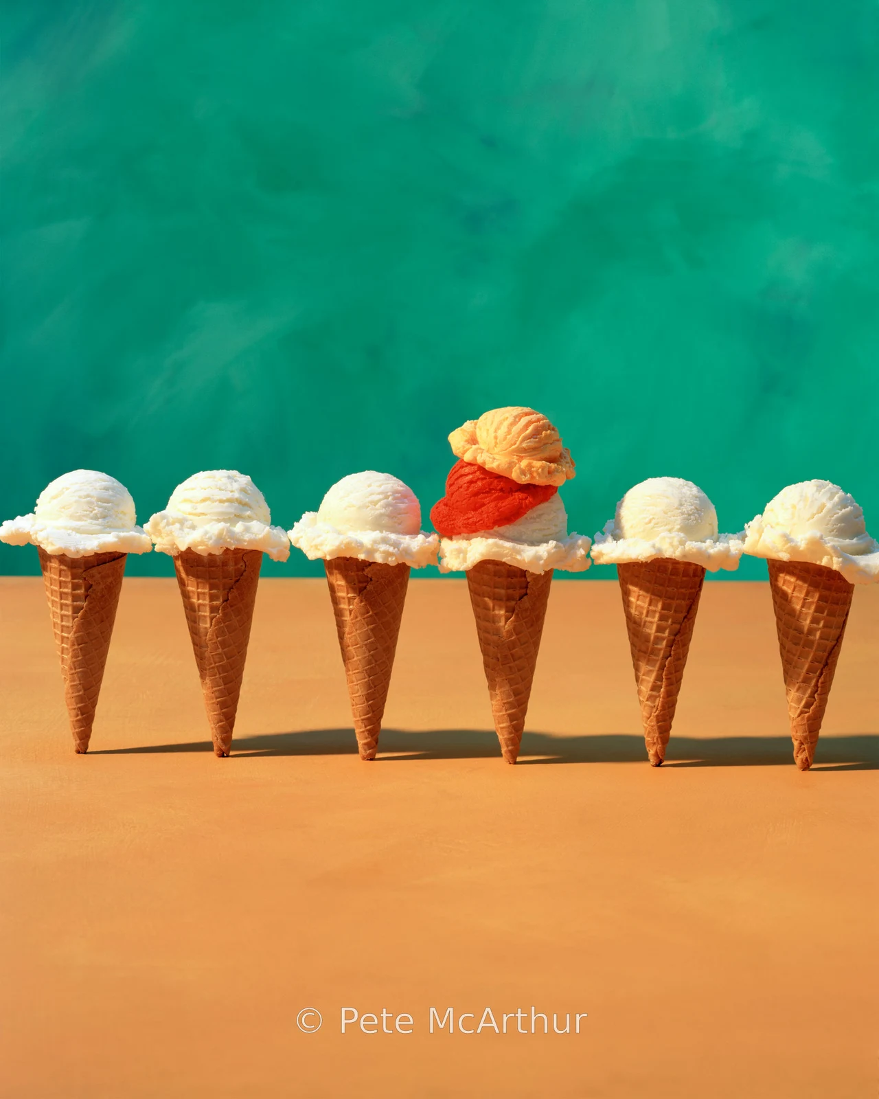 A row of standing ice cream cones includes one with multiple colorful scoops.